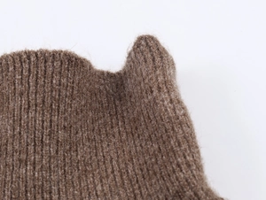 Macro d'un bonnet en tricot marron café montrant la texture douce et les côtes fines