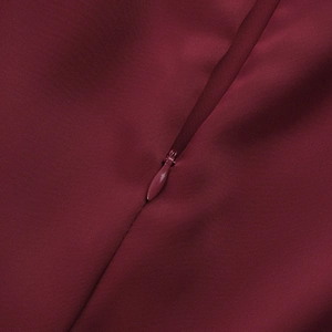 Detailed close-up of invisible zipper on elegant burgundy slit evening dress