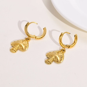 Detail of gold mushroom drop earrings featuring textured caps and polished finish