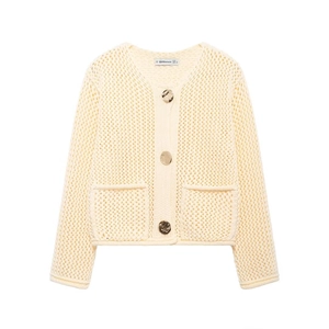 Détail d'un cardigan en maille crème avec de gros boutons marron et des poches plaquées