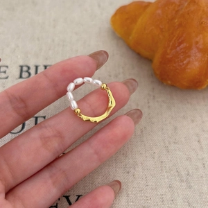 Detailed view of the irregular gold metal texture and white pearls on the ring