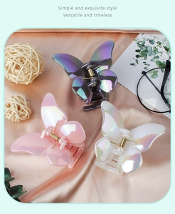 Three pearl-effect butterfly hair clips in purple, pink, and white on soft satin fabric
