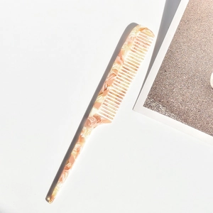 Detail eines rosa marmorierten Acetatharkamms mit langem Stiel zum Stylen der Haare
