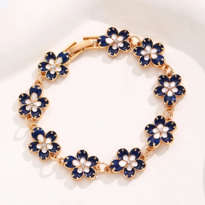 Close-up of a golden flower bracelet with blue and white enamel and zircon center