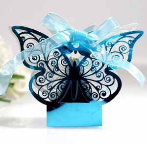 Macro detail of laser-cut blue butterfly favor box with elegant pearl finish and ribbon