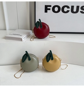 Detailed close-up of apple-shaped mini bags in red, green, and yellow with gold chains