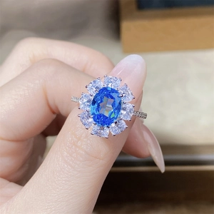 Detailed view of aquamarine halo ring with pear-cut diamonds on finger