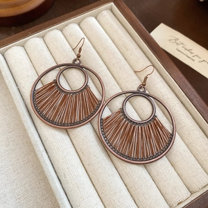 Close-up of bohemian hollow round earrings with brown woven thread in a jewelry box