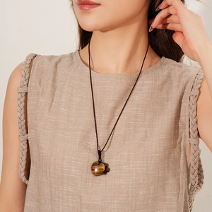 Close-up of heart-shaped tiger eye stone pendant on dark brown braided cord necklace
