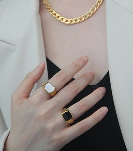 Detalle de anillos de sello dorados con esmalte negro y nácar blanco en una modelo