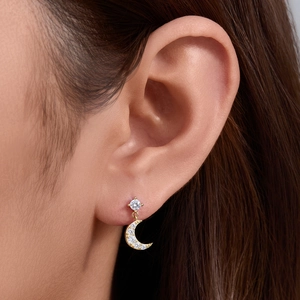 Close-up of golden moon stud earrings with white zircon on model's ear showing elegant detail