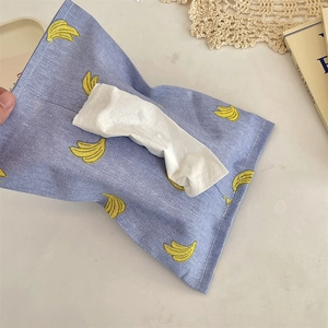 Blue car tissue box holder with yellow banana pattern on a stylish home desk setup