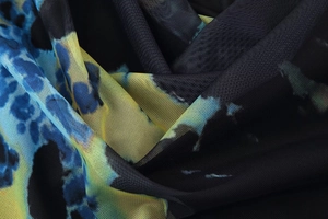 Gros plan du tissu en maille noire avec imprimé abstrait bleu et jaune et texture respirante