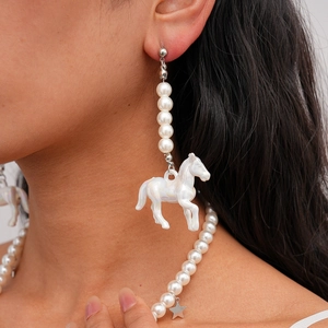 Détail du collier et des boucles d'oreilles en perles avec breloques étoile et cheval