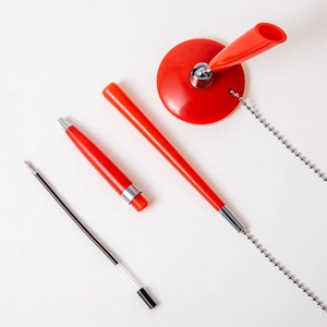 Red desk security pen with adhesive base and metal chain, component parts layout view
