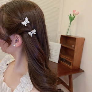 Model wearing a small butterfly pearl hair claw and matching earrings in a home setting