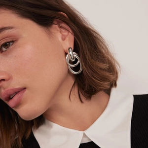 Detail of silver triple hoop earrings worn by a model showing texture and scale
