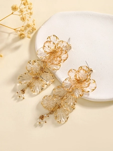 Detail of gold floral earrings with clear petals and delicate beaded tassels on a tray