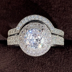 Macro shot of silver halo ring set with round main stone and arched pavé bands