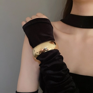 Detail of a minimalist wide golden cuff bracelet with high-gloss polished finish for women