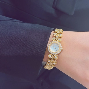 Close-up of luxury gold vintage watch featuring a rhinestone bezel on a woman's wrist