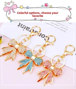 Detail of crystal bowknot keychains in white, blue and pink with golden metal rings