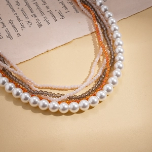 Makroaufnahme einer mehrlagigen Kette mit Perlen und geschliffenen Glasperlen auf Buch