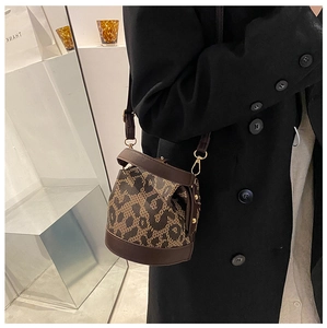 Close-up of retro leopard print bucket bag with brown leather trim and gold hardware