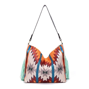 Detail of woven bohemian tote bag featuring geometric patterns and mint green tassels