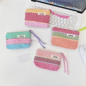 Detail view of four colorful woven striped makeup bags with zippers on a white desk