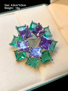 Detailed macro view of a floral wreath brooch with purple and green zircon stones