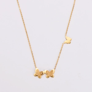 Detail of gold butterfly necklace featuring frosted textures and polished metal finish