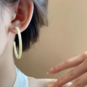Close-up of model wearing retro C-shaped marble resin earrings in cream ivory