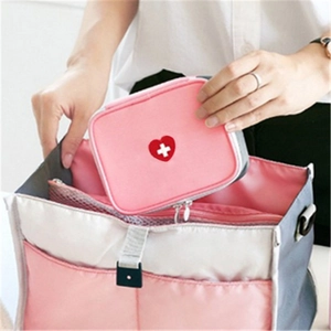 Portable pink travel first aid kit with heart cross logo being tucked into a storage bag
