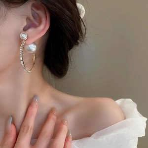 Close-up of elegant double pearl gold hoop earrings with sparkling rhinestones on model