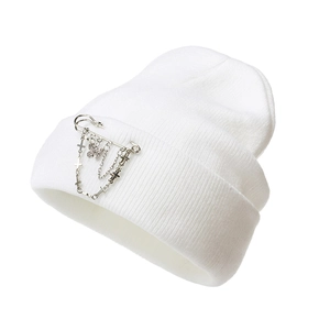 Detail of white knit beanie featuring silver butterfly and cross chain pin accessories