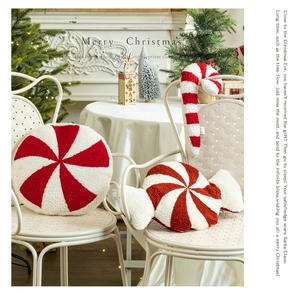 Detail of red and white candy-shaped plush Christmas pillows on a white chair