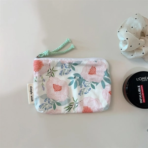 Detailed top view of floral cotton zipper pouch with pink peonies and green cord pull