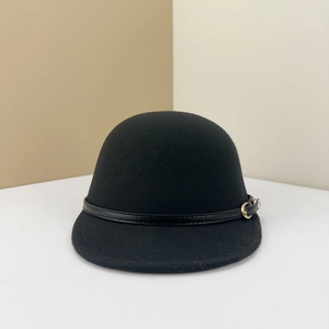 Détail d'un chapeau melon en laine noire avec sangle en cuir et boucle dorée minimaliste