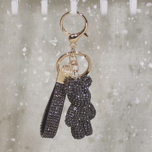 Detailed view of dark grey rhinestone bear keychain with gold metal clasp and strap
