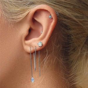 Detailed macro shot of S925 silver opal earrings and long chain tassels on ear