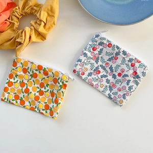 Detailed top view of floral cotton coin purses with orange and berry prints on table