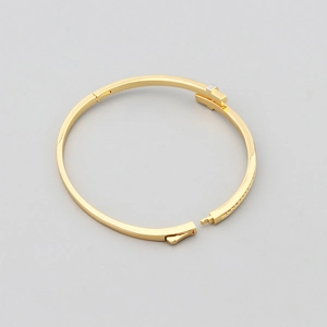 Close-up of a gold-plated copper bangle with T-shaped opening and inlaid zircon detail