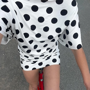 Top-down view of a white short-sleeve mini dress with black polka dots on a bike