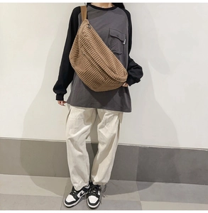 Brown corduroy crossbody bag worn by model showing textured crescent shape and size