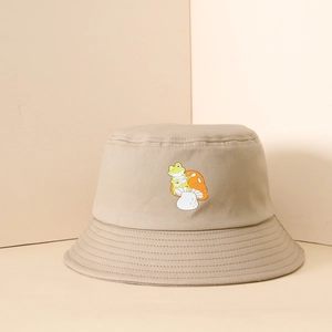 Detailed view of frog and mushroom embroidery on a beige canvas bucket sun hat