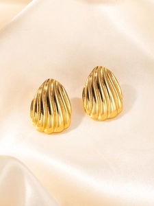Macro shot of gold shell earrings with ribbed texture on cream silk fabric