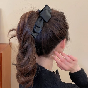 Détail d'une élégante pince à cheveux en satin noir sur une coiffure ondulée