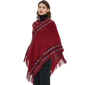 Ethnic knit poncho with diamond patterns and rainbow trim tassels on white background