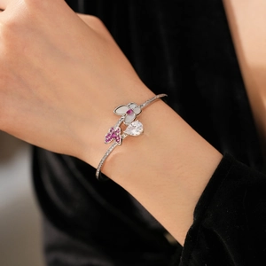 Detailed shot of open bangle featuring pink zircon butterfly and teardrop stone accents